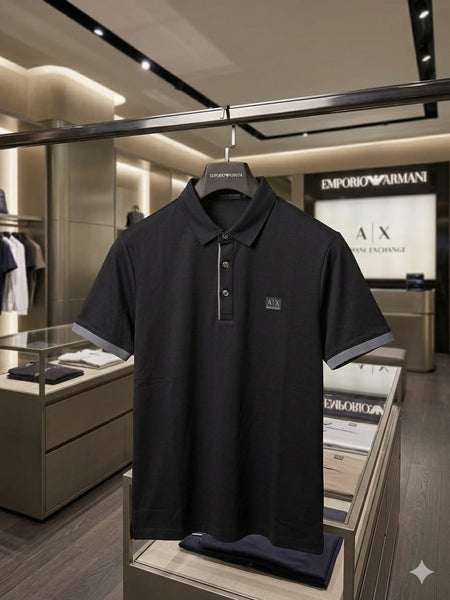"A|X Armani Exchange men's black short-sleeve polo shirt with contrast grey tipping on collar and cuffs, AX logo chest patch and metallic placket buttons, displayed on hanger in Armani Exchange boutique"