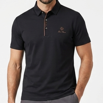 men's polo shirt hanging on a wooden hanger against a gray textured wall. The shirt features a classic spread collar, a partial button placket with decorative striped trim, and a small embroidered logo on the left chest. A magazine display is visible in the lower right corner of the background.